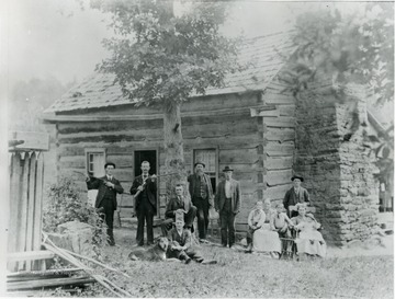 A group of people standing in front of a log cabin.