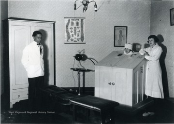 The interior of a massage salon. Woman inside a box with two attendants standing nearby.