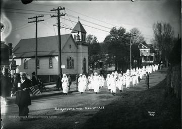 Women in white dresses marching in the Armistice Day Parade in Morgantown, West Virginia.