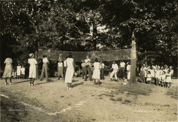 A group of African-Americans playing volleyball while their children watch.