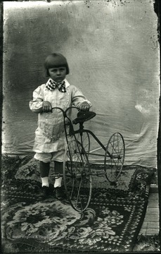 An unidentified little boy with a tricycle.