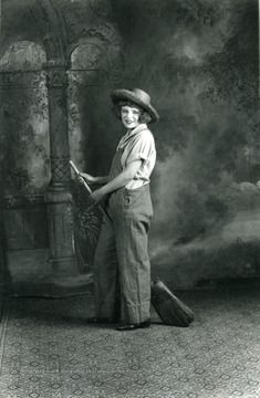 Women in a farm costume holding a broom.