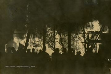 People stand around to watch the building completely engulfed in flames.