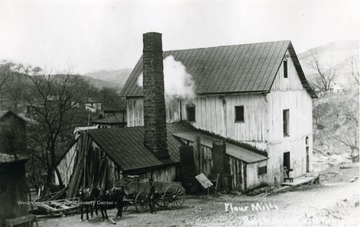 Man standing next to horse and carriage in front of the flour mill.