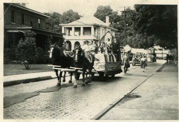 People sitting on the back of a horse drawn parade float in Barbour County.