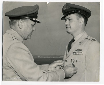 Soldier stands as another soldier places his military award on his uniform.