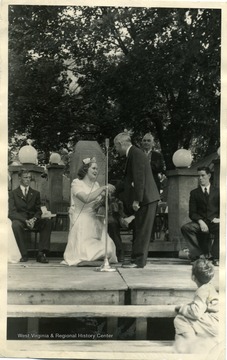 Man helps Queen up after she has been crowned.