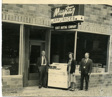 At far right is A. Roy Scott, owner of Scott Maytag.  The man and woman to his left are unidentified, but the man may be a representative of the Maytag company.