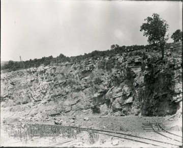 Rail line runs along cut in hillside.