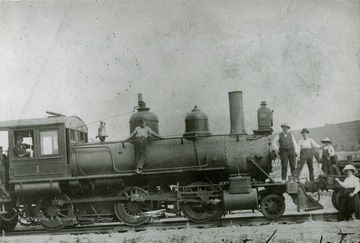 Scene of people getting their picture taken with the first railroad engine to enter Moorefield.