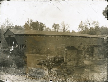 A view of Maulsby Bridge, a wooden covered bridge on the West Fork River in Harrison County. 'Erected in 1856 by Elmore Hart and repaired in 1911 by C. A. Short.'
