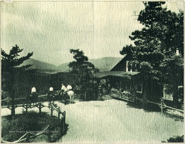 People on horseback next to a lodge look down into the valley.