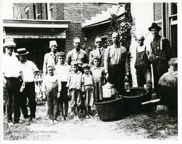 Group portrait celebrating Prohibition Days at the Old Jail Building in Hardy County, West Virginia. Back row: left to right: Joe Chipley, M. Samuels, M. Cain, Lew Coucbs, M. Dasher, George Paskel, Jailer Tom Lakin, and Raw Sager. Kids: Lantz Paskel, Chas Paskel, Marion Paskel, and Dasher girls.
