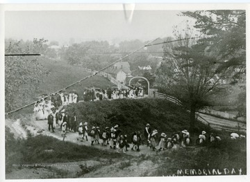 'A Confederate Decoration Day procession in 1908. Picture from the original glass plate negative by M. Alexander. Until after World War I Decoration Day in Moorefield was always held on June 6th every year. Flowers and wreaths were always prepared by Daughters of the Confederacy. Appropriate services were held at Inskeep Hall with addresses by invited speakers and a procession then proceeded to the cemetery where further services were held and graves decorated, children carrying the wreaths and flowers. When the custom was discontinued most of the ceremony was also discontinued.'