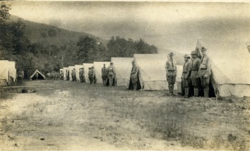 Military School Students stand outside of their bivouac shelters for inspection.