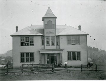 Four men are seen in front of the building while a horse grazes nearby. It was Established in 1910.