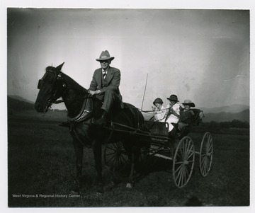 Three girls in the buggy, while a man rides the horse.