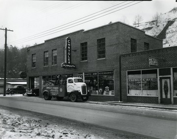 View of the War Motor Service building with a wrecker parked out in front.