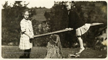 A postcard photograph of Maggie and Helen Ballard on a seesaw.