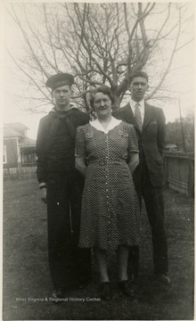 Billy B. Lingo on the left side of his mother and Paul Lingo on the other side, stand together outside for a photo.