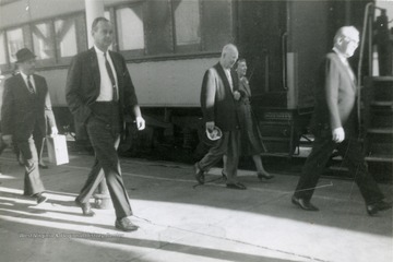 President Eisenhower and wife walk alongside a train car.