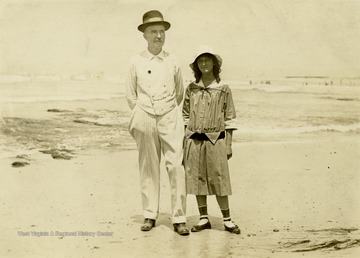 A picture of S. S. Ballard and a young girl, standing on the beach together. 'See my little sweetheart, 13 years old. I brought her from Texas to her mother in Los Angeles. They are happy now. She calls me Papa.'