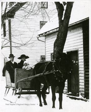 'Fred and Mollie Hammer and their son, Lacy in front of Ike Ruddle home and slaughter house, Franklin, Pendleton County, W. Va.