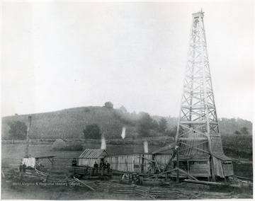 'Burning off the gas from an oil well in Ritchie County.  This is a wood derrick. The flaming torches are to remove the gas out of the oil; a waste that isn't occurring today; it is too precious.'