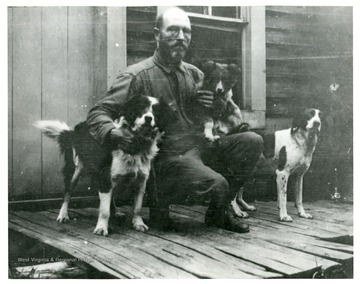 A portrait of Adam T. Dodrill and three dogs on a porch in Webster County, West Virginia.