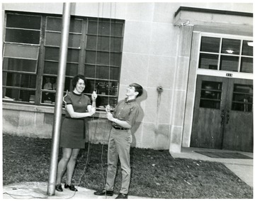 Record Book Presidents David Gilkeson (1967-68) and Barbara Tenney (1968-69) hoist the American Flag.  Barbara Tenney was the Secretary of Student Council and David Gilkeson was the President of Student Council.