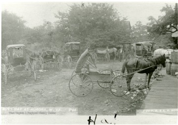 View of horse and buggies.  Photograph reads 'Sold by P.R. &amp; A. A. McCrum' (right hand side), 'A busy day at Aurora, W. Va.' (left hand side)