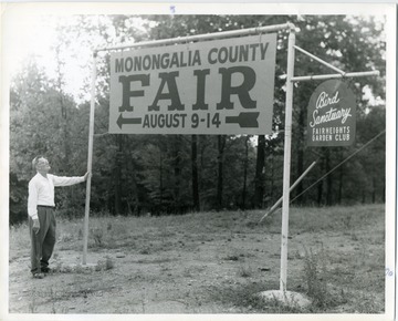 Signs say: 'Monongalia County Fair, August 9-14.  Bird Sanctuary, Fairheights Garden Club.'