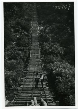Two men are talking while standing on a wooden bridge that overlooks the Cheat River in Monongalia County, West Virginia. Photograph is taken from Hugh Maxwell's book. 