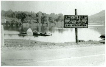 View of a sign by the Monongahela River that reads 'Cross the Ferry Shortcut to Suncrest, Evansdale and Morgantown.'