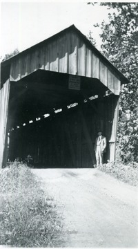 View of man standing at entrance of bridge.
