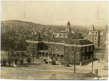 View of the east side of the Agricultural Experiment Station Building.  Three early automobiles are parked on College Avenue across from the building. 