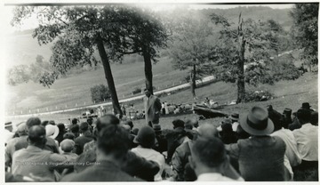 Group seated on a hillside listening to speaker.