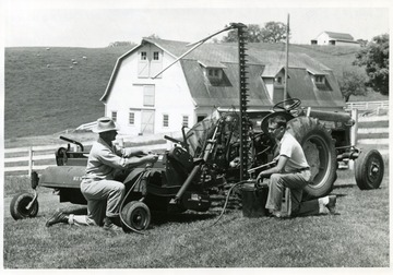 'Charles Boyles (left) and Kenneth Elliott, greasing a hay crusher, are getting ready for today's Livestock Field Day which will be held out at the University Animal Husbandry farm on Stewartstown Road beginning at 10 o'clock. Boyles, superintendent of the livestock farm, and Elliott, an assistant agricultural engineer, will be demonstrating this and other machines at the farm this afternoon.'