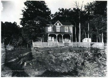 A woman is holding a baby on the porch of the house.