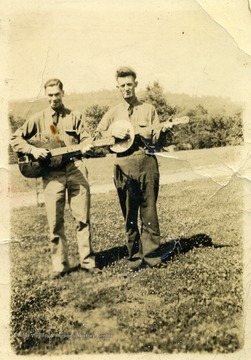 Clyde Evans holding a guitar with a friend holding a banjo at Camp Crawford.  Camp Crawford was a base for Company 1512 in the Charleston District, Fifth Corps Area.