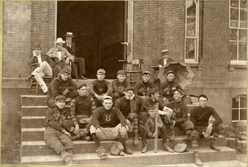 Inscribed on the back of the photograph, "Back row left to right- Llewelyn, McWhorter, Lawhead, Miller, Shelby.  Middle row- Anderson, Mitchell, Dent, Middleberg.  Front row-  Lowe, Wilhelm, Pratt.  The bat boy- Hartigan. Not sure of the interested spectators.  The one in the Iron hat with his legs crossed- Ed Naret.  Back of the umbrella in the sailor- Hieronimous, a law student.  Man with spinnach- Douthat, a professor.  Light Fedora, bow tie and leer, unknown."
