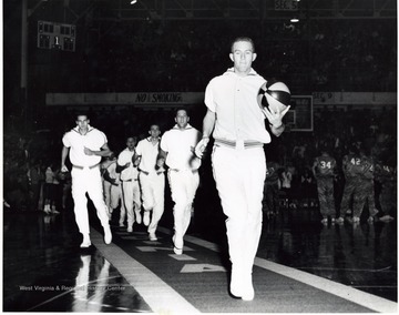 Willie Akers leads the team down the carpet and Jerry West is on the left. The carpet is rolled out before each home game for the WVU team to enter on to the court. This is one of the best traditions in NCAA basketball. 