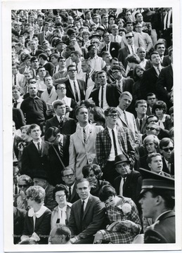 Students cheering on the Mountaineers during a football game. 'Taylor Publishing Company, Job Number 07206, Picture Number 38a, Page Number 254, West Virginia University, Morgantown, West Virginia.'