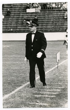 Budd Udell is entering the field to direct the band at a football game.