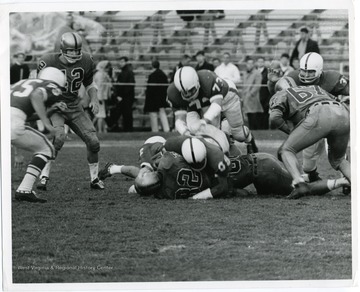 Tailback Garrett Ford (32) is tackled while Dick Rader (42) looks on and Ken Woodeshick (67) throws block.
