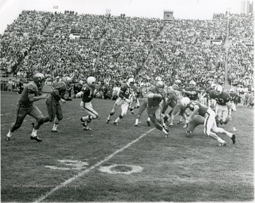 Dick Rader (42) carries ball as Larry Canterbury (87), Roger Alford (66), Ken Woodeshick (67), and Pat Buratti (75), rush to his aid.