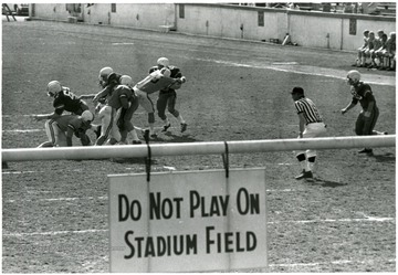 Players seen beyond 'Do Not Play on Stadium Field' sign.