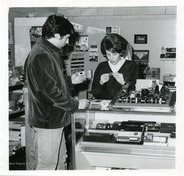 Eugene Solaro, a customer at the University Bookstore, looking at slides with the sales clerk.