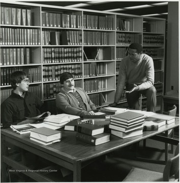 View of three men at table in law library.