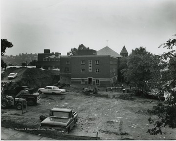 View of buildings on University Avenue, opposite E. Moore Hall, etc.  Cafeteria building destroyed, Health Center building being moved to where former stood.  Background- Main library, Chemistry, shops, Reynolds, Administration building.